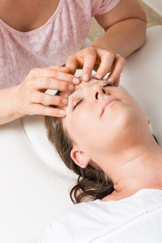 woman laying down getting forehead massaged