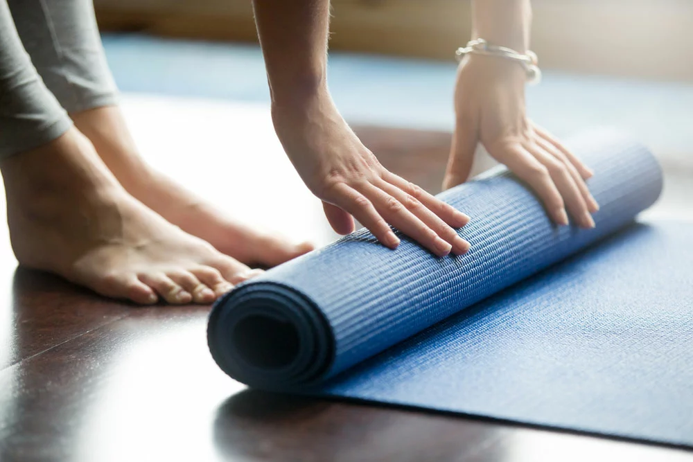 hands rolling up yoga mat